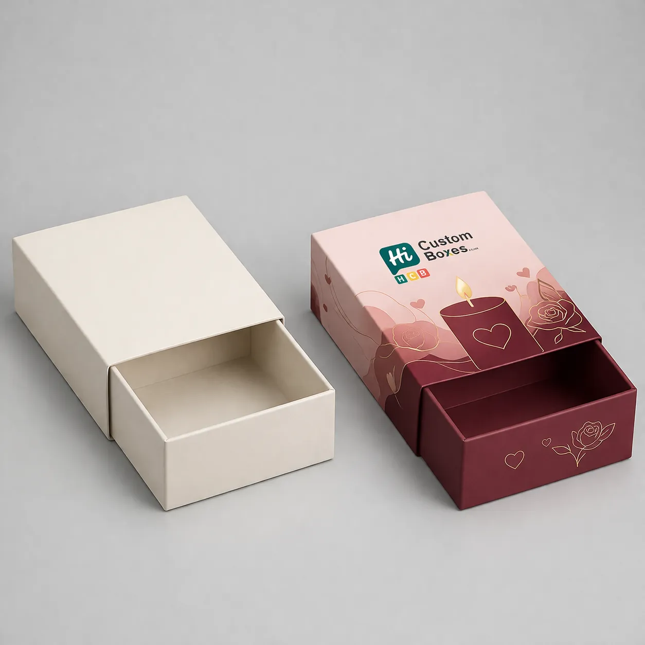 Two sliding drawer boxes, one cream and one pink with a lit candle and rose design. class=